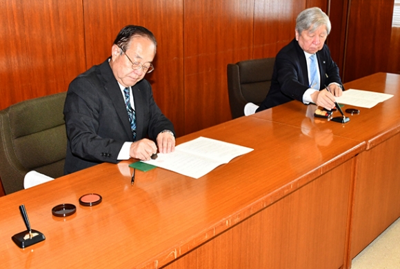 連携協定の調印に臨む山田教育長(左)と観山学長=土岐市文化プラザで