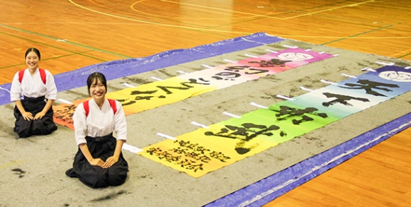 ライトアップイベントで飾られるのぼり旗に信長の格言をしたためた友田さん（左）、仁木さん＝岐阜市太郎丸の岐阜女子大で