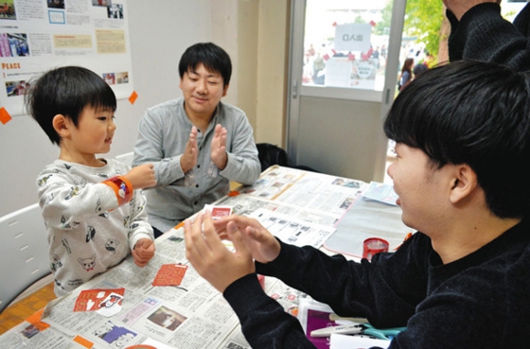 ペットボトルを再利用してリストバンドを作った親子と中京大の学生（右）＝西区のなごのキャンパスで