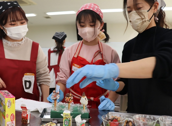 明治の製品を使ってチョコレート菓子を作る親子ら＝日進市岩崎町の愛知学院大で