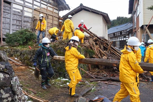 木材を運び出して倒壊した家屋を片付ける学生ら＝穴水町河内で