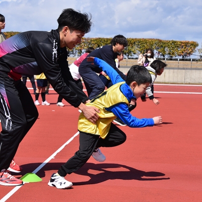 学生のサポートを受けながら速く走るこつを学ぶ児童ら＝多治見市星ケ台で