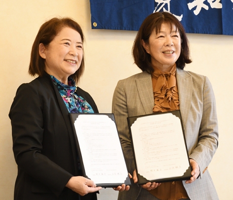 署名した協定書を見せる愛大の上田法務研究科長（右）と名市大の野中学部長＝東区の愛大車道キャンパスで