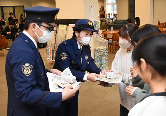 学生に啓発品を配布する署員ら＝北名古屋市の名古屋芸術大で