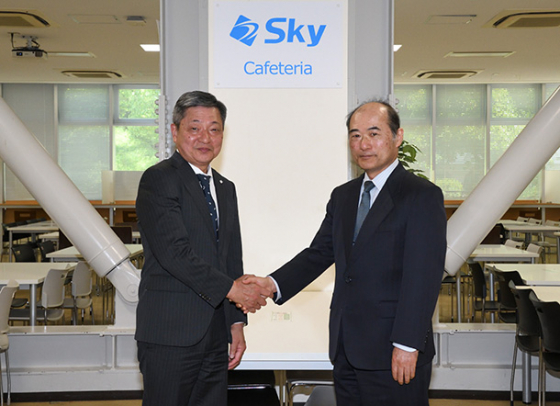 大食堂で握手する小畑学長（右）と寺下執行役員＝昭和区の名古屋工業大で