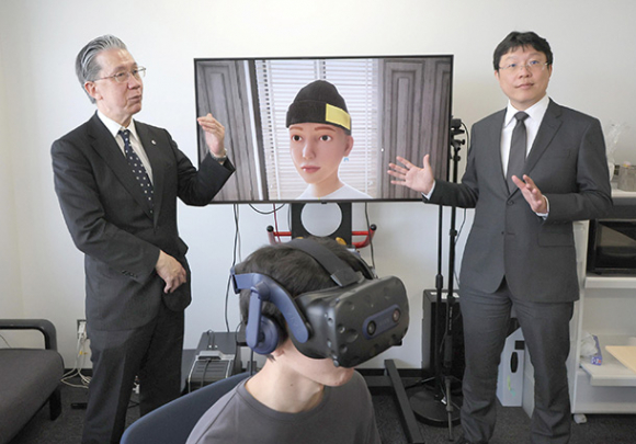 模擬患者のアバター(後方)を仮想空間に映すシステムを開発する藤田医科大の石原慎教授(左)と名古屋工業大の李晃伸教授 =名古屋市昭和区の名工大で