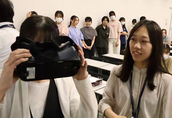 ＶＲ専用のゴーグルを使い、車両衝突を疑似体験する学生（左）ら＝守山区の金城学院大学で