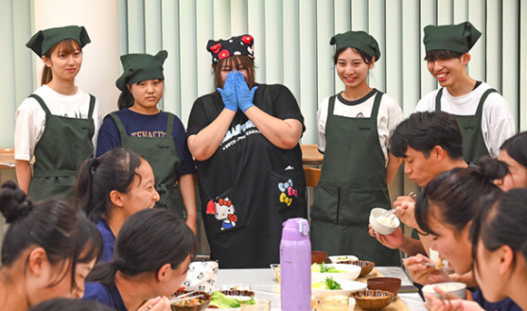 陸上部員たちが食事を食べる様子を見守る学生たち(奥側)=一宮市の修文大で