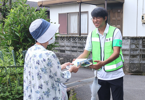 高齢者に防犯や事故防止を呼びかける学生（右）＝四日市市あさけが丘で