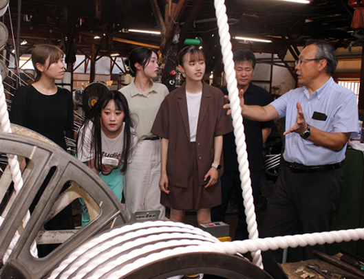 稲葉隆志・稲葉製綱社長（右）の説明に耳を傾ける学生ら＝蒲郡市で