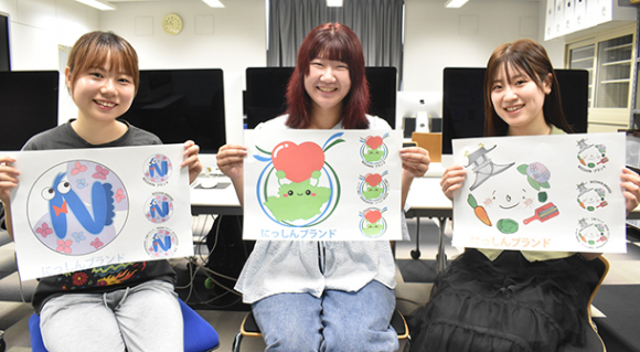 ロゴマークの候補を紹介する（左から）伊東さん、川瀬さん、北畠さん＝日進市岩崎町の名古屋学芸大で