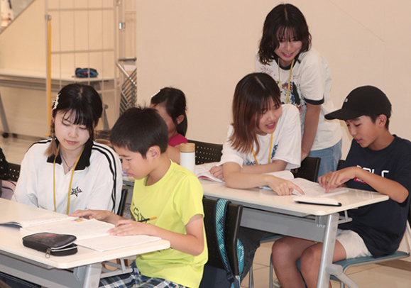 名城大の学生から勉強を教えてもらう小学生＝東区のイオンモールナゴヤドーム前で