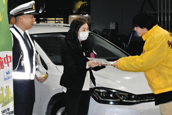 給油に訪れたドライバー(中)に啓発チラシを手渡す名城大の学生(右)と杉原署長=天白区植田3の渡部石油で