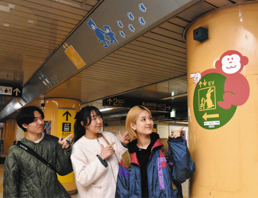 改札階の案内表示を紹介する(左から)江上さん、石河さん、渡辺さん=千種区の市営地下鉄東山線東山公園駅で