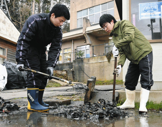 側溝にたまった泥をかき出す学生＝輪島市深見町で