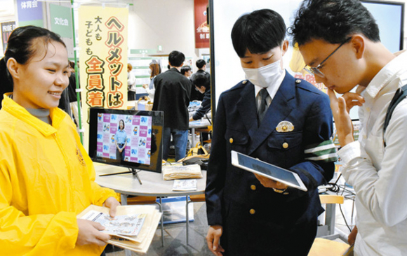 学生（右）に自転車の交通ルールに関するクイズを出題する署員とボランティア協議会のメンバー＝天白区の名城大天白キャンパスで
