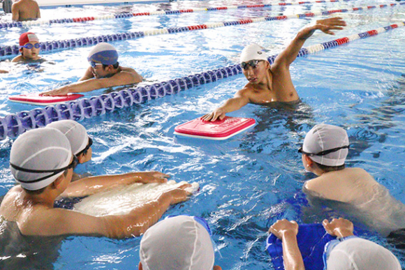 手本を見せながら、クロールの泳ぎ方を指導する中京大の学生ら＝豊田市貝津町で