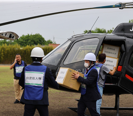 藤田医科大、三重大、浜松医科大が連携した訓練で、浜松医大からヘリで運ばれた医療物資を運ぶ人たち＝名古屋市緑区の藤田医大で