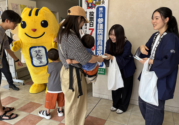家族連れに参院選投票を呼びかけるめぐるメンバー=各務原市の中部学院大各務原キャンパスで