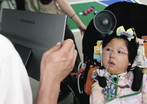 視線入力で動物のクイズアプリを楽しむ女児＝千種区の椙山女学園大で