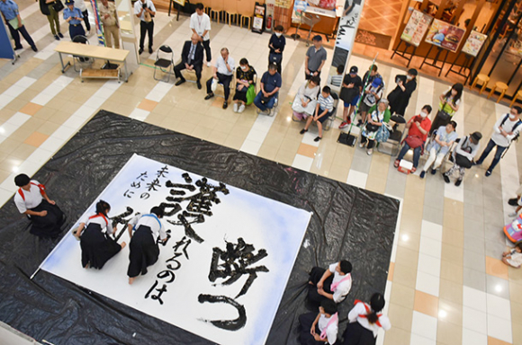 来店客を前に書道パフォーマンスを披露する部員たち＝千種区千種２のイオンタウン千種で