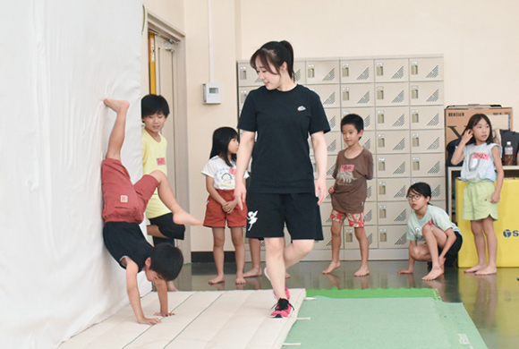 側転に挑戦する子どもたちを指導する鈴木さん（中）＝日進市の愛知学院大で