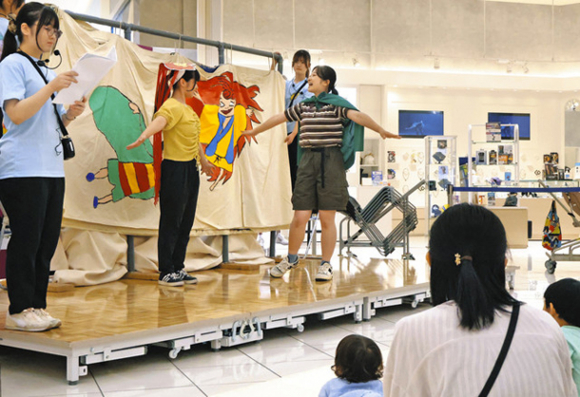 大型布芝居で絵本の「めっきらもっきらどおんどん」を披露する名古屋学芸大生=東区のイオンモールナゴヤドーム前で