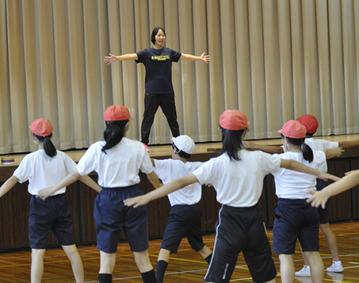 壇上の学生と「からだじゃんけん」をする児童＝中津川市神坂小で