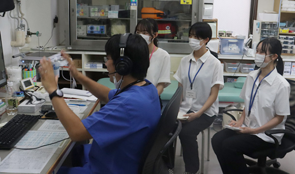 池田さん（左）が遠隔で診察する様子を見学する学生＝鳥羽市桃取町の桃取診療所で