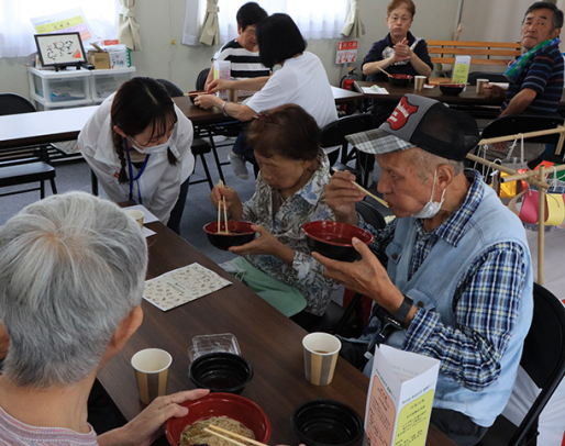 学生らと懇談しながら、そうめんを味わう仮設住宅の住民ら=石川県穴水町大町で