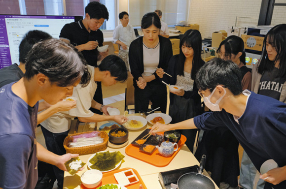陸上養殖の「うるみえび」と「知多クールサーモン」を使った学食メニュー候補を試食する学生ら=いずれも名古屋市昭和区の南山大で