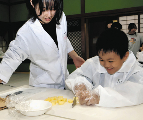 実験用のパイナップルを切る児童（右）＝金沢市片町の金沢学生のまち市民交流館で