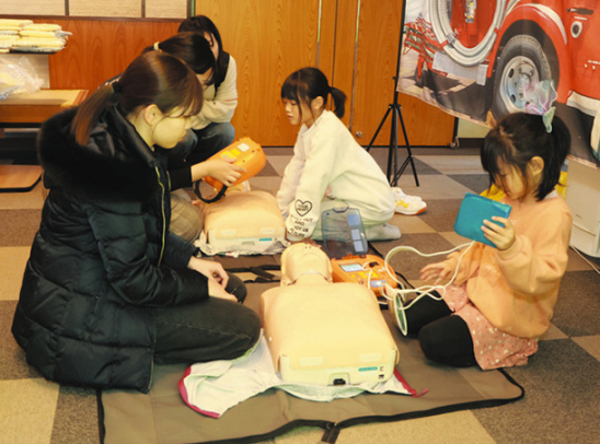 子どもにＡＥＤの使い方を教える学生＝石川県珠洲市上戸町で