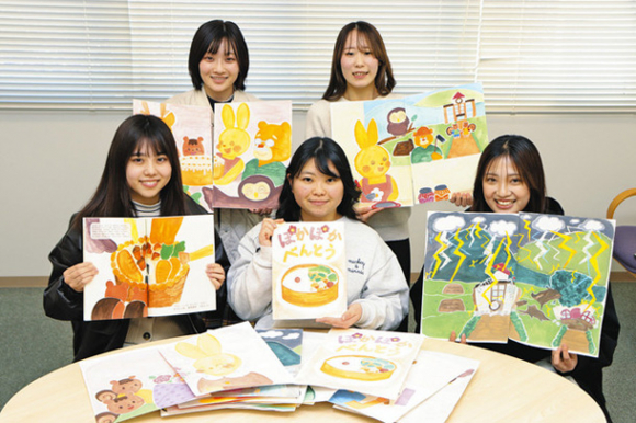 完成した絵本や、試作段階の絵を手にする学生ら=岡崎市舳越町の愛知学泉大で