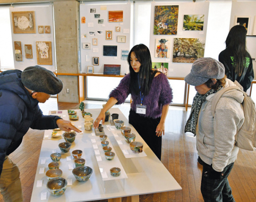 展示販売の会場で、来場者に自身の作品について解説する学生（中）ら＝愛知県長久手市の文化の家で