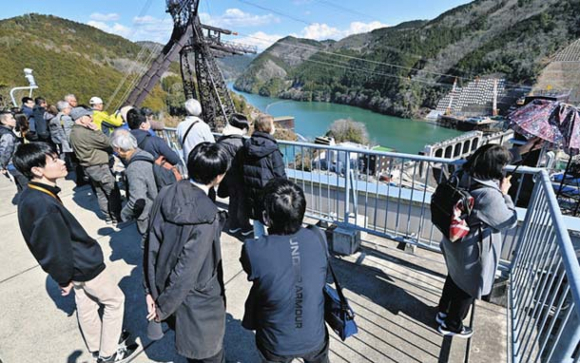 丸山ダムと新丸山ダムを見学する参加者と大学生＝岐阜県八百津町の丸山ダム管理支所で