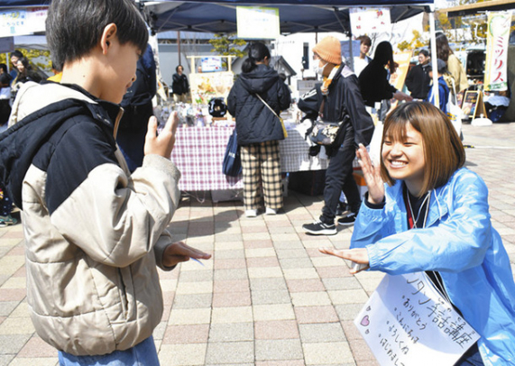 子どもに簡単な手話を教える学生（右）＝長久手市勝入塚で