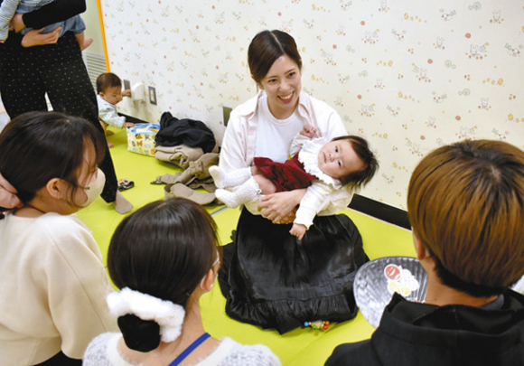 子どもをあやしながら、学生に向けて日々の育児について語る母親＝名古屋市中区栄で