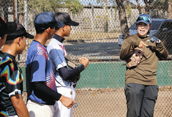 子どもたちにソフトボールを指導する佐藤はづきさん(右)=2月20日、タイ中部スパンブリ県で
