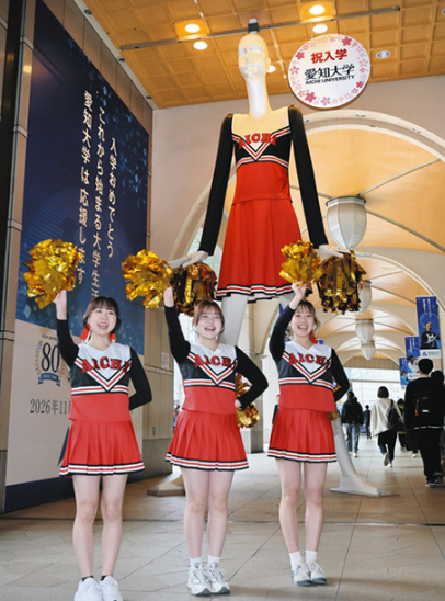大学に向かう新入生らにエールを送る応援団チアリーディング部とナナちゃん人形=名古屋・名駅で