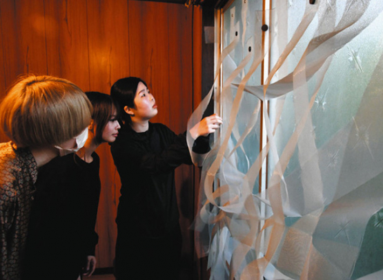 網戸に使われる網を帯状にした作品を展示している平本さん（右）＝北区清水の「みかんハウス」で