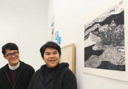 故郷の風景をイメージした作品（手前）を紹介するドゥアンケアウさん（右）＝北名古屋市徳重の名古屋芸術大で