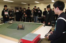 自作の無線操縦型ロボットをリング上で競わせる参加者=輪島市文化会館で
