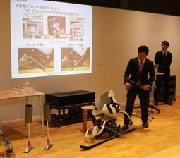 チェアスキー(手前)の試作用具について発表する学生=野々市市の金沢工業大で