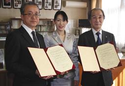 協定書に調印した竹本学長（右）と鈴木校長（左）。中央はまほろばさん＝名古屋市西区の名古屋西高で