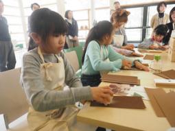 木片を紙やすりで磨く子供たち＝３日、下呂市萩原町四美の南飛騨健康増進センターで