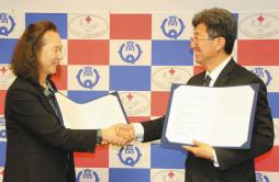 協定書を手に握手を交わす日本赤十字豊田看護大の鎌倉学長（左）と豊田高の野村校長＝豊田市白山町の日本赤十字豊田看護大で