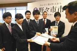 粟貴章市長(右)に完成した英語版パンフレットを手渡す学生代表=野々市市役所で
