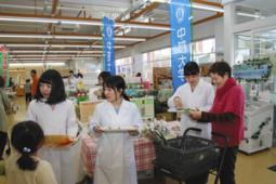 野菜ソースの試食を勧める学生たち＝春日井市松本町１のぐぅぴぃひろばで