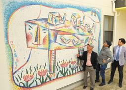 園の外壁に設置された壁画「夢見る鳥」の出来栄えを確かめる（左から）吉岡さん、曽根さん、織田さん＝大治町花常の大治はなつね保育園で